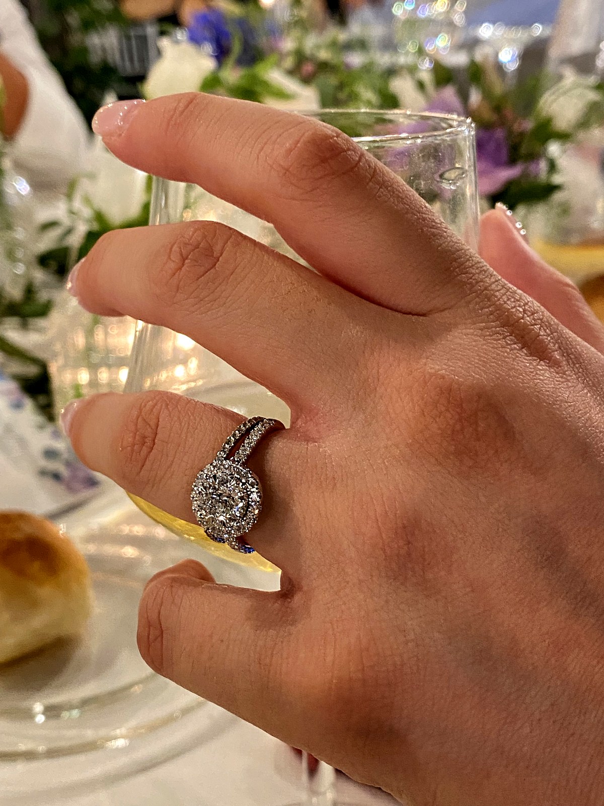 Anello con diamante centrale e corona di diamanti, abbinato a una fedina pavé, indossato a cena