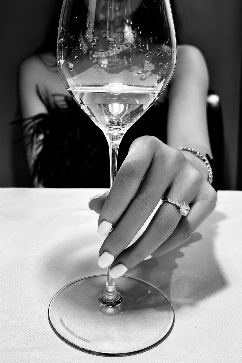 Mano con anello solitario che regge un calice, in bianco e nero